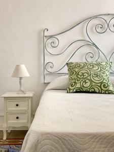 Cama con almohada verde y mesita de noche con lámpara en Casa Chiara en Lipari