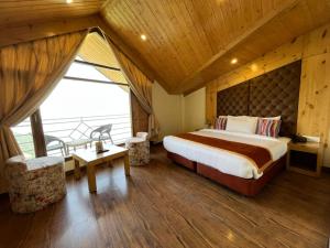 a bedroom with a large bed and a balcony at Kufri Pacific Resort in Mundaghat 