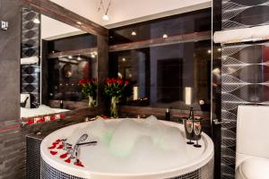 a bath tub in a bathroom with a large mirror at Komorowski Luxury Guest Rooms in Krakow