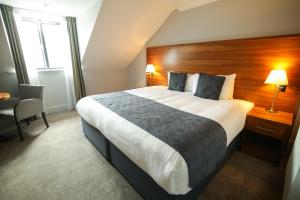 een hotelkamer met een groot bed en een bureau bij Old Thorns Hotel & Resort in Liphook