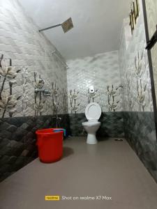 a bathroom with a toilet and a red trash can at Palolem Sunrise Apartment in Palolem