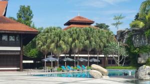 a resort with a pool with chairs and umbrellas at Garden View Pulai Springs Resort in Skudai