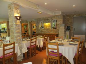 a restaurant with white tables and chairs and a stone wall at Le Mas de la Frigoulette in Sanary-sur-Mer