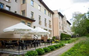 a group of tables with umbrellas in front of a building at Marta Medical in Połczyn-Zdrój