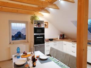 una cocina con armarios blancos y una mesa con comedor. en Ferienwohnung Störmthaler See en Großpösna