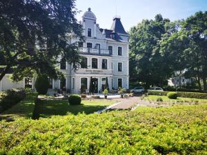 uma grande casa branca com uma torre em Hotel Fryderyk em Duszniki Zdrój