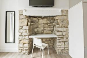 una chimenea de piedra con una silla blanca delante de ella en Dizzy Lows en Swanage