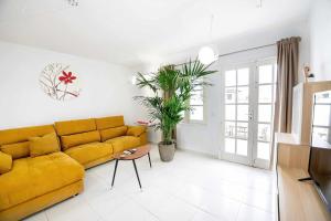 ein Wohnzimmer mit einem gelben Sofa und einem Tisch in der Unterkunft Le Family Palms My Home in Playa Honda