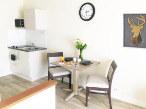 a small kitchen with a table and chairs and a clock at Villa Rose de Mons - Résidence Services Senior in La Brede