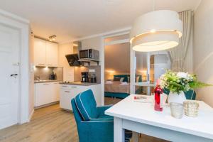 eine Küche und ein Wohnzimmer mit einem Tisch und blauen Stühlen in der Unterkunft Villa Albertine, App. 10 in Ahlbeck