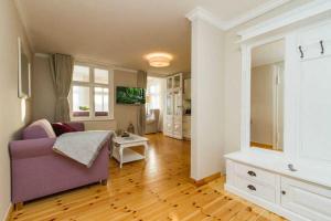 uma sala de estar com um sofá roxo e piso em madeira em Villa Albertine App 08 em Ahlbeck