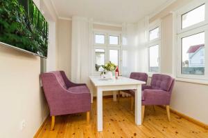uma sala de jantar com uma mesa branca e cadeiras roxas em Villa Albertine App 08 em Ahlbeck