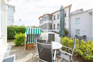 eine Terrasse mit einem Tisch, Stühlen und einem Sonnenschirm in der Unterkunft Villa Albertine, App. 02 in Ahlbeck