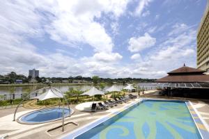 a pool at a hotel with chairs and umbrellas at Grand Margherita Hotel in Kuching