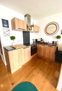a kitchen with wooden cabinets and a black counter top at L IROIZH CONCARNEAU VUE MER STUDIO STANDING PARKING draps inclus in Concarneau