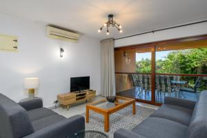 ein Wohnzimmer mit Sofas, einem TV und einem Balkon in der Unterkunft San Lameer Villa 1933 - 2 Bedroom Classic - 4 pax - San Lameer Rental Agency in Southbroom