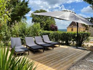 een groep stoelen en een paraplu op een houten terras bij Beautiful 4 bedroom country cottage sleeps 7 in Saint-Cybranet