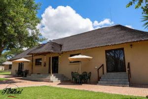 a house with chairs and umbrellas in front of it at Fumani Game Lodge in Modimolle
