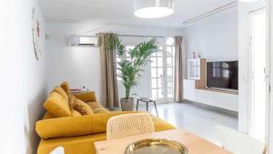 ein Wohnzimmer mit einem gelben Sofa und einem Tisch in der Unterkunft Le Family Palms My Home in Playa Honda