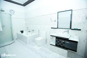 a white bathroom with a sink toilet and a mirror at Chamsha Hotel in Anuradhapura