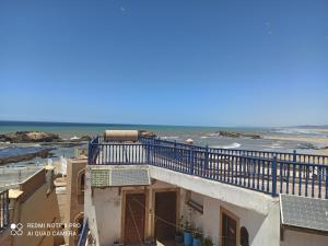 a building with a balcony with the ocean in the background at Riad La Rose Des Vents in Essaouira