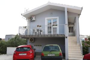 two cars parked in front of a house at Apartmani Eni in Seget Vranjica