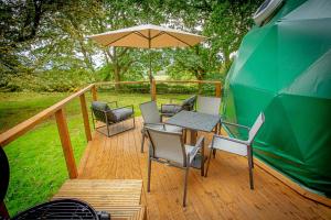 a deck with a table and chairs and an umbrella at Finest Retreats - Hever Luxury Dome 