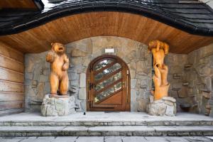 twee standbeelden van beren op de voorkant van een deur bij Aparthotel Delta Royal in Kościelisko