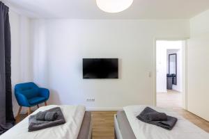a bedroom with two beds and a blue chair at Glück Auf Appartements Schleiermacherstraße Duisburg in Duisburg