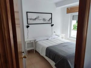 a white bedroom with a bed and a window at Apartamentos Trevias in Trevías