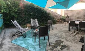 a patio with chairs and a table with an umbrella at Petit paradis in Vic-Fezensac