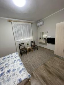 a bedroom with a bed and two chairs and a kitchen at New Bazaar Rooms in Tirana