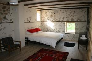 ein Schlafzimmer mit einem Bett mit roten Kissen und einem Stuhl in der Unterkunft Hangjik (Little Inn) 