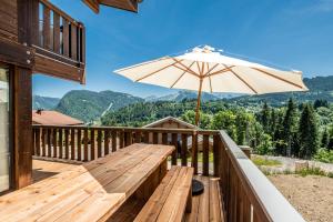 drewniany taras z ławką i parasolem w obiekcie Chalet Cipolin Morzine - by EMERALD STAY w mieście La Côte dʼArbroz