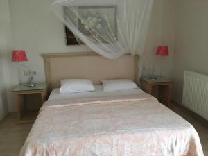 Melaike Hotel في فوكا: غرفة نوم مع سرير مع مصباحين على طاولتين