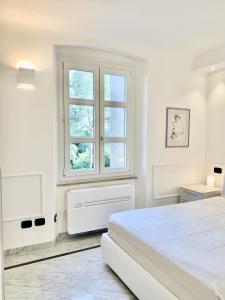 een witte slaapkamer met een bed en een raam bij Lerici WhiteHouse in Lerici