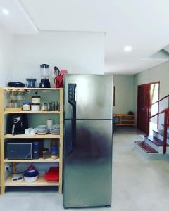 a kitchen with a stainless steel refrigerator next to a shelf at Casa Verde Maré in Pipa