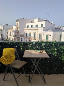 una mesa y una silla en un balcón con vistas a los edificios en Cà Mea, en Alberobello