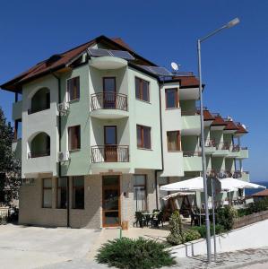 a large white building with a balcony and tables at Family Hotel Amore in Byala