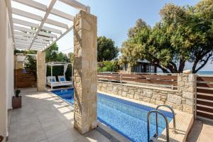 a villa with a swimming pool and a pergola at Azure Beach Villas in Kissamos