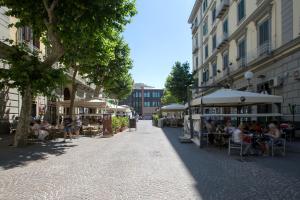 a street with people sitting at tables and umbrellas at CocoMorghen Apartment in Naples