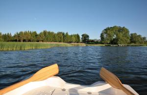 a boat on a lake with its paddles in the water at Siedlisko Miluki - Apartamenty nad Jeziorem z Jacuzzi & Sauną in Ełk