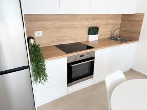 a kitchen with white cabinets and a sink and a stove at Sea view Apartment Elite2 in Sarandë