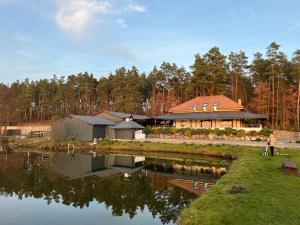 une femme debout devant une maison près d'un lac dans l'établissement Rybaczówka Golub-Dobrzyń, à Golub-Dobrzyń