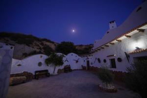 a night view of a building with a moon in the sky at CASA CUEVA LOS HONORIOS in Cortes de Baza