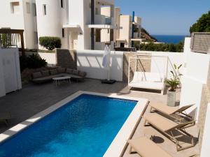 een villa met een zwembad en een patio met stoelen bij Villa Vidal in San Jose de sa Talaia