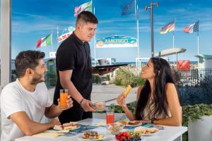 Un groupe de personnes assises autour d'une table et mangeant de la nourriture dans l'établissement Feel Good, à Rimini