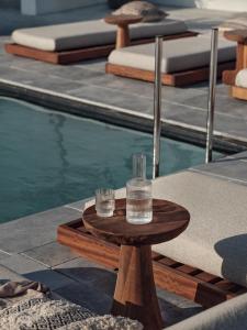 two glasses on a table next to a swimming pool at Casa Cook Mykonos - Adults Only in Ornos