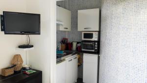 ビアリッツにあるBelle Suite Aptの白いキャビネット、電子レンジ、テレビ付きのキッチンが備わります。
