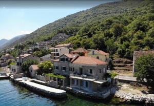 a large house in the water with a mountain at House with a pier in Donji Morinj